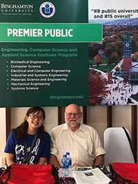 Professor Roy McGrann with a student in Vietnam in front of a Binghamton University poster promoting our programs.
