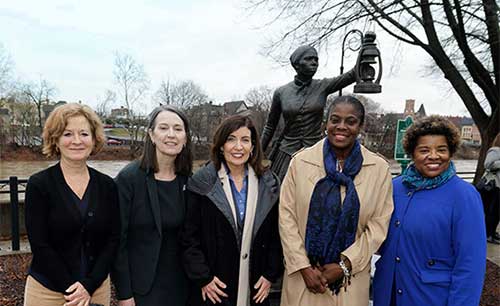 Women in front of statue of woman holding lamp