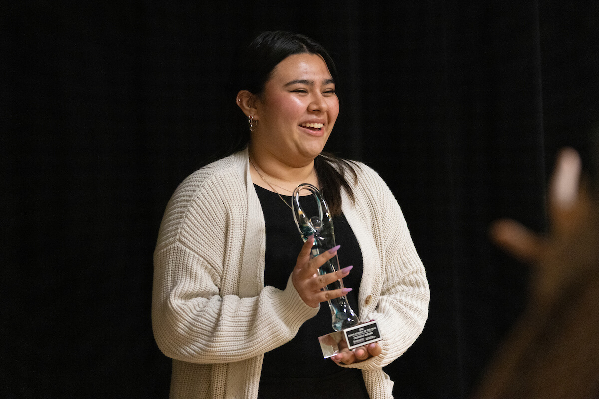 A young female student holding an award