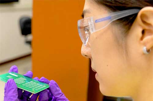 women in lab with purple gloves