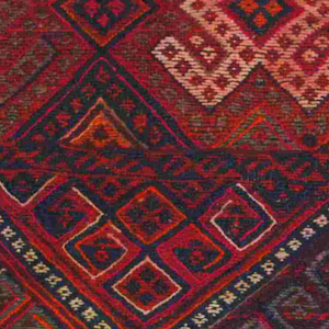 Black, orange, purple, and pink Kurdish rug with a geometric design and multicolored tassels. 