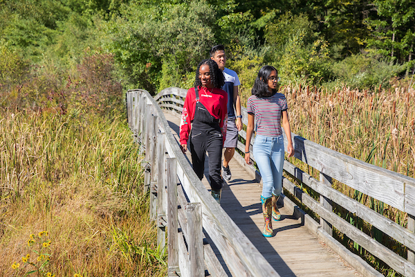 Three students hike in the Nature Preserve in 2019