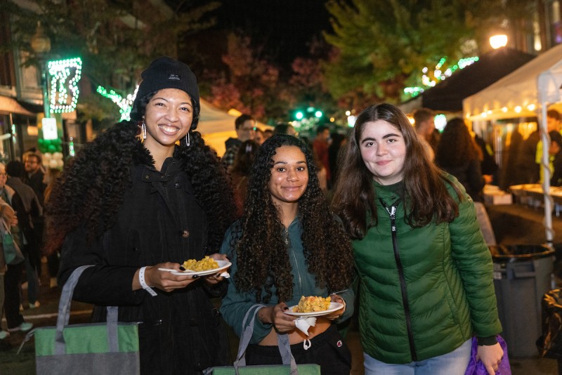 Three friends smile with a couple of plates of food at the 2022 Binghamton Block Party