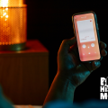 A close up image of a person of color holding a phone in a dimly lit room.