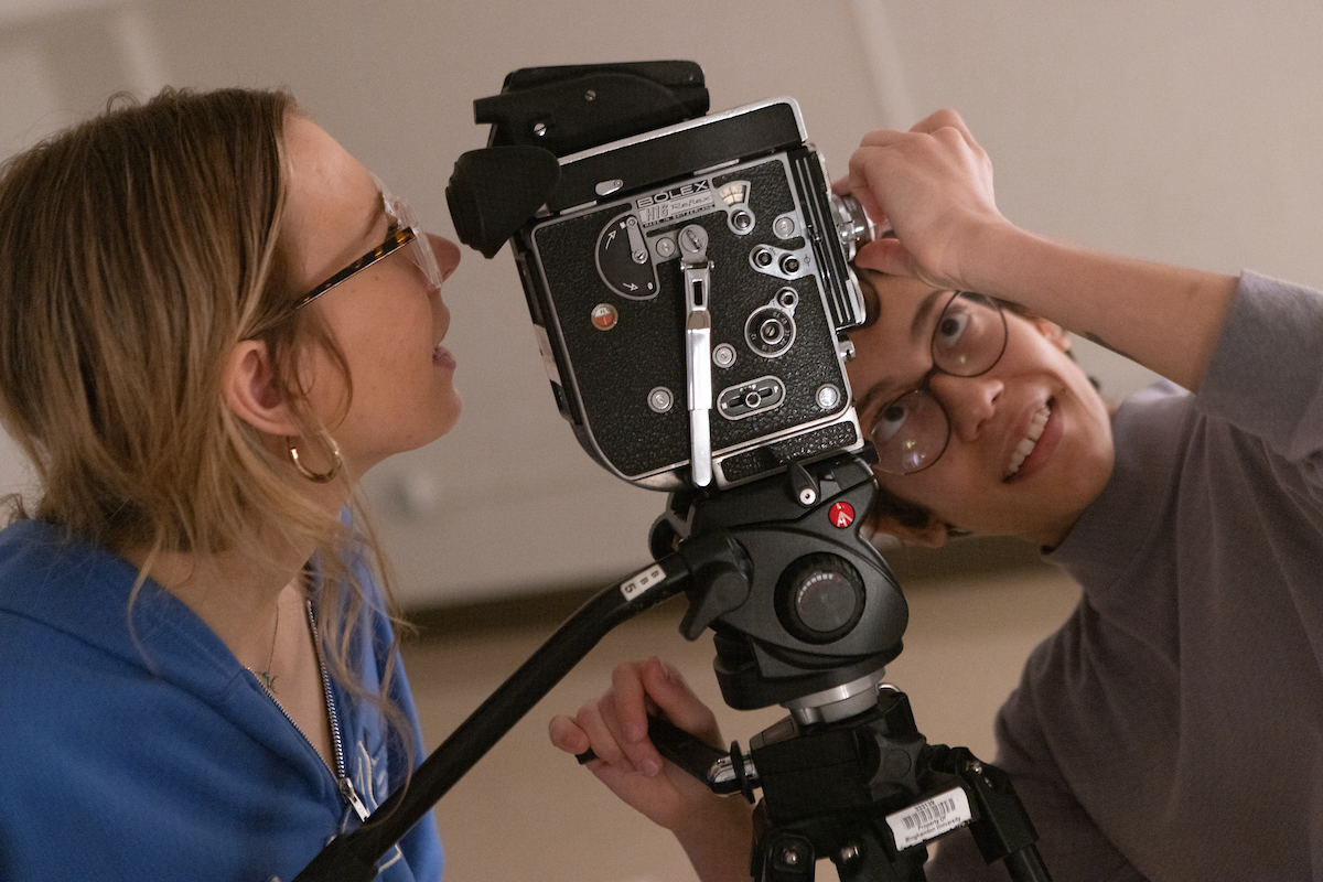 Cinema students Christine Szafranski (wearing blue) and Alicia Mujynya make adjustments to a 16mm motion picture camera.