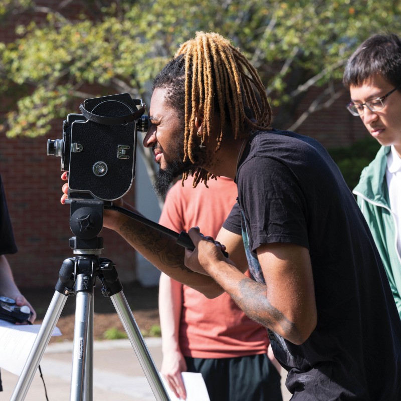 A cinema student uses a camera to film a scene.