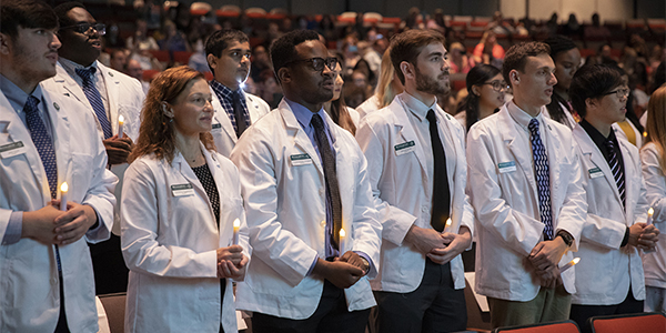 PharmD students new to the School of Pharmacy and Pharmaceutical Sciences at Binghamton University pass the Light of Knowledge and recite their Pharmacy Oath at their White Coat Ceremony, held Aug. 25, in the Osterhout Concert Theater.