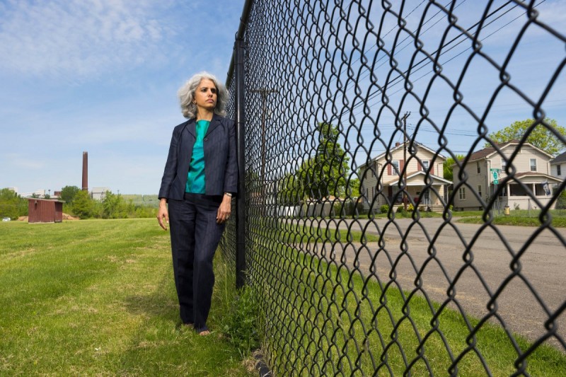 Economics Professor Neha Khanna stands in a Johnson City playground that overlooks a power plant.