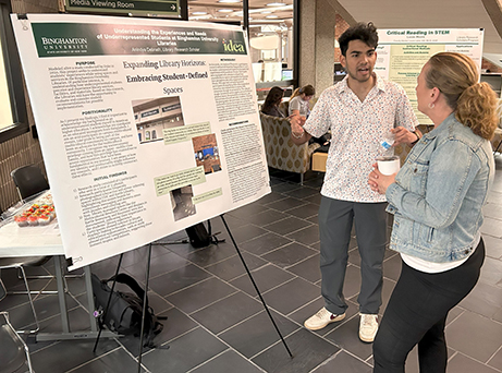 Libraries research scholar Anindya Debnath shares his research poster with Health Sciences Librarian Laura Lipke.