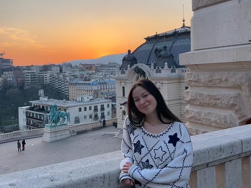 Caroline Portman in front of Buda Castle in Budapest, Hungary. The sprawling castle and palatial complex sits atop  Castle Hill and overlooks the Danube river.