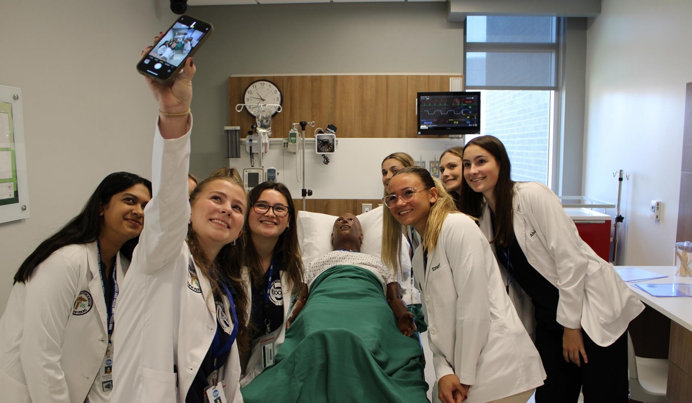 Several of the BOCES New Visions students pose for a selfie with a high-fidelity manikin in the Skills Lab.