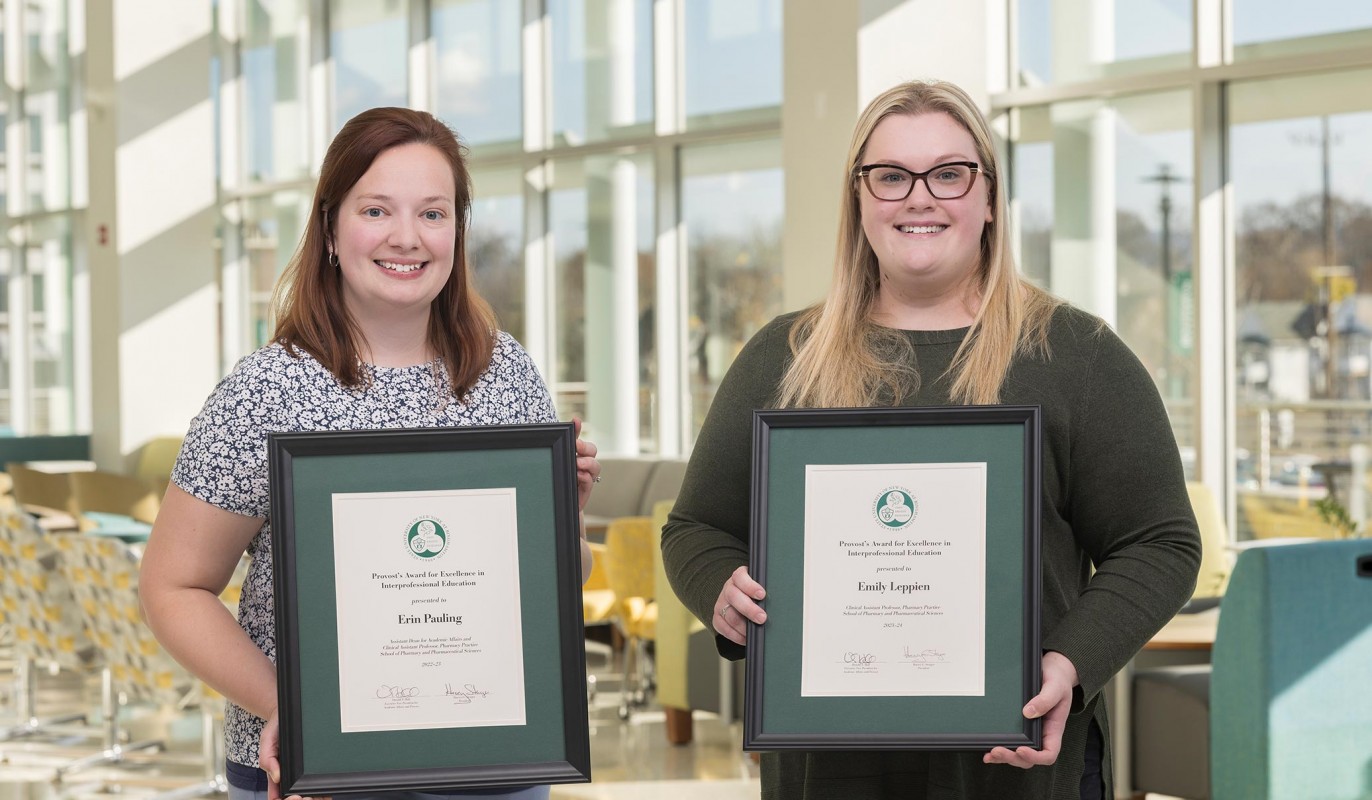 Clinical Associate Professors Erin Pauling (left) and Emily Leppien (right) stand with their Provost awards for Interprofessional Education inside the Binghamton University School of Pharmacy and Pharmaceutical Sciences.